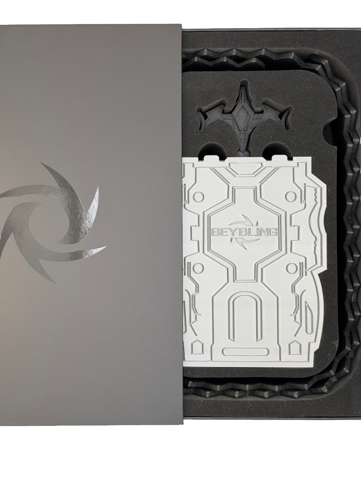 BeyBling gift packaging with a gray swirl-logo box lid beside a black foam tray holding an embossed white BeyBling insert card